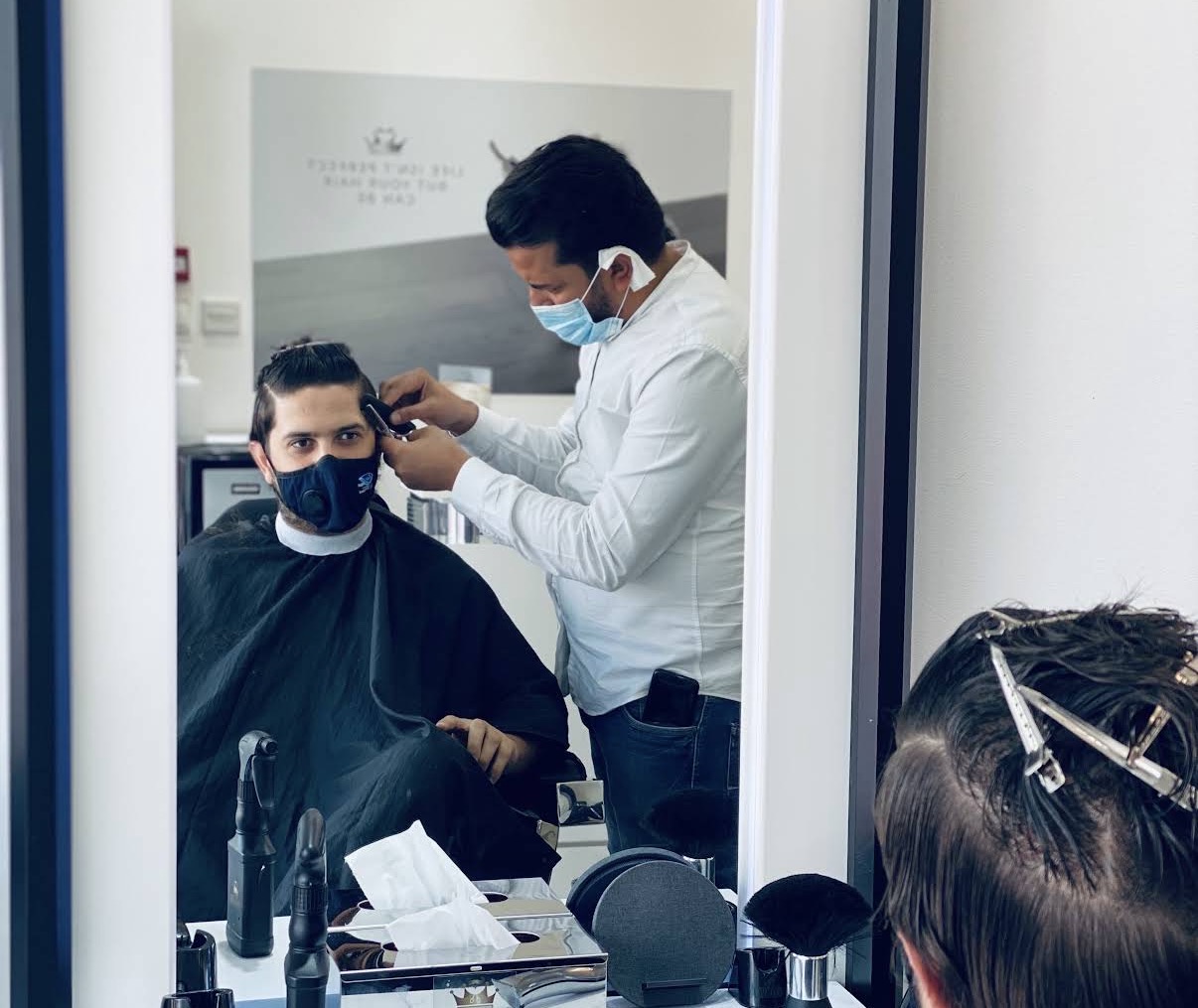 Barber cutting a customer's hair, seen through the mirror